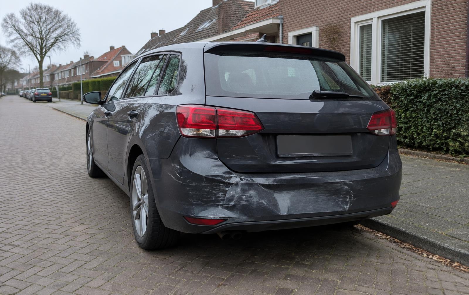 Geparkeerde auto met schade aan de achterbumper in een woonstraat